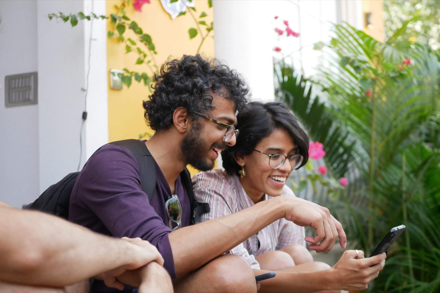 Two people laughing together while looking at a phone
