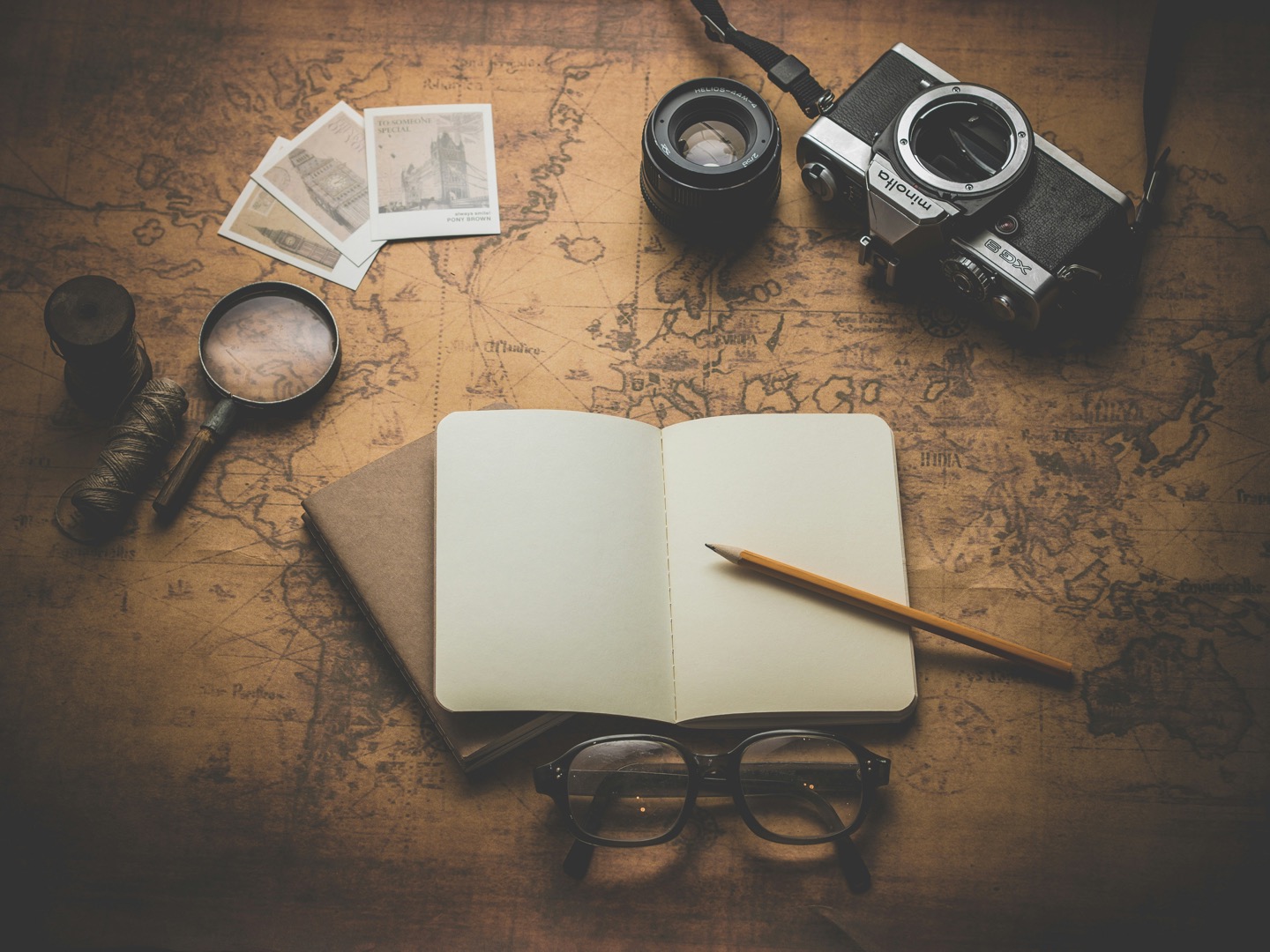 Open journal, camera and polaroids on a vintage map