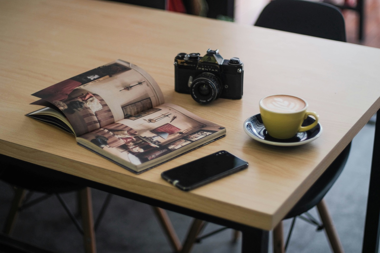 Open photo book on a table with a camera and a latte