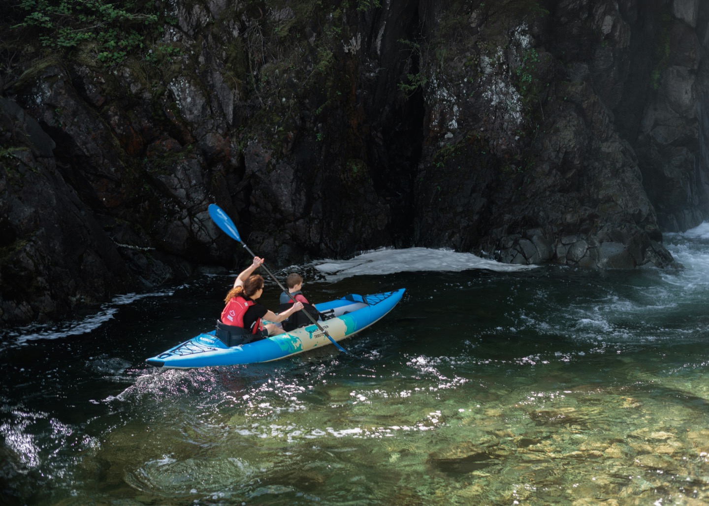 Two people kayaking through a dramatic river gorge